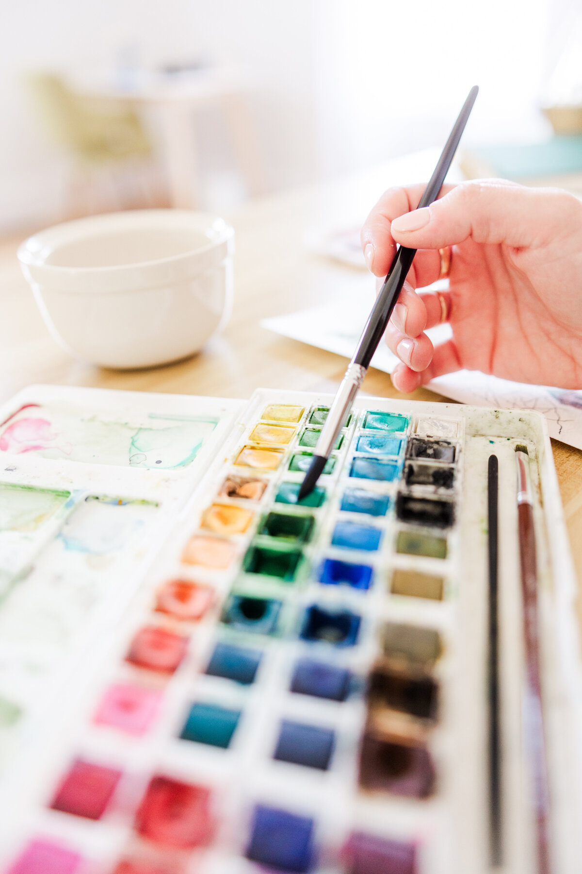 close up of an artist dipping her paint brush into a paint palette