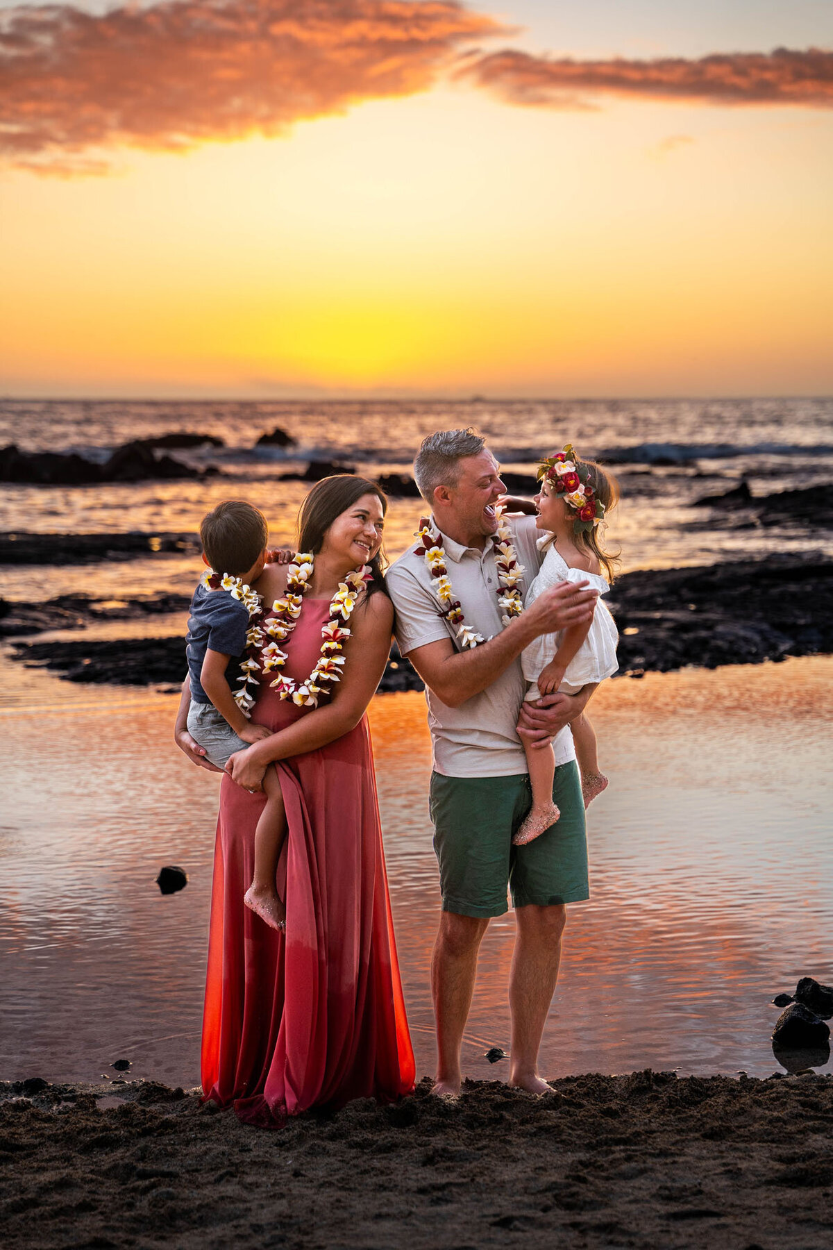 family pictures in Hawaii of parents holding two kids wearing leis