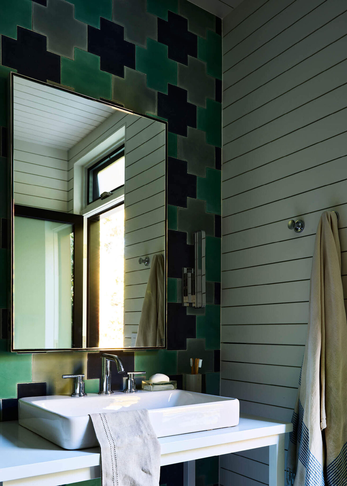 New construction home designer creates a bathroom with white shiplap and custom Popham tiles in navy, green, and grey for a modern pool house in Hingham, Massachusetts.