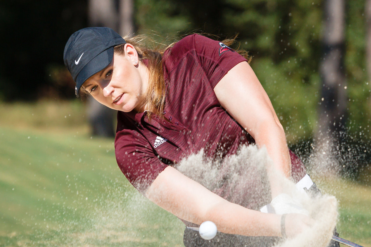 University of Mobile women's golf team player hitting the ball out of the sandtrap.