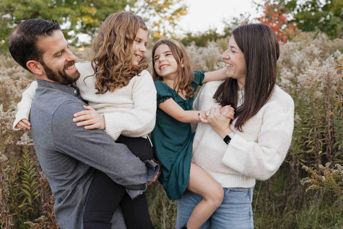 Mom, dad and two daughter laugh candidly during fall mini session at Acacia Reservation in Cleveland.