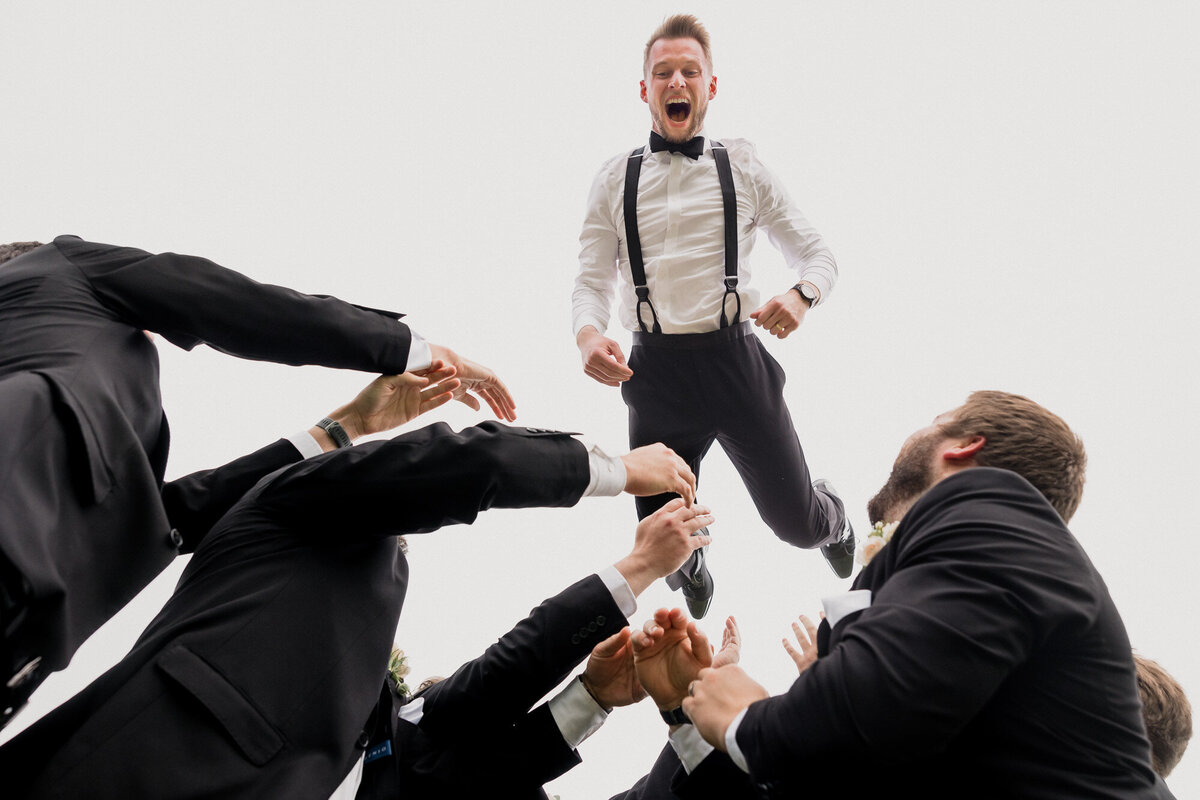 Groom gets thrown in the air by his groomsmen during his wedding at the Chevy Chase Country Club in Wheeling, Illinois