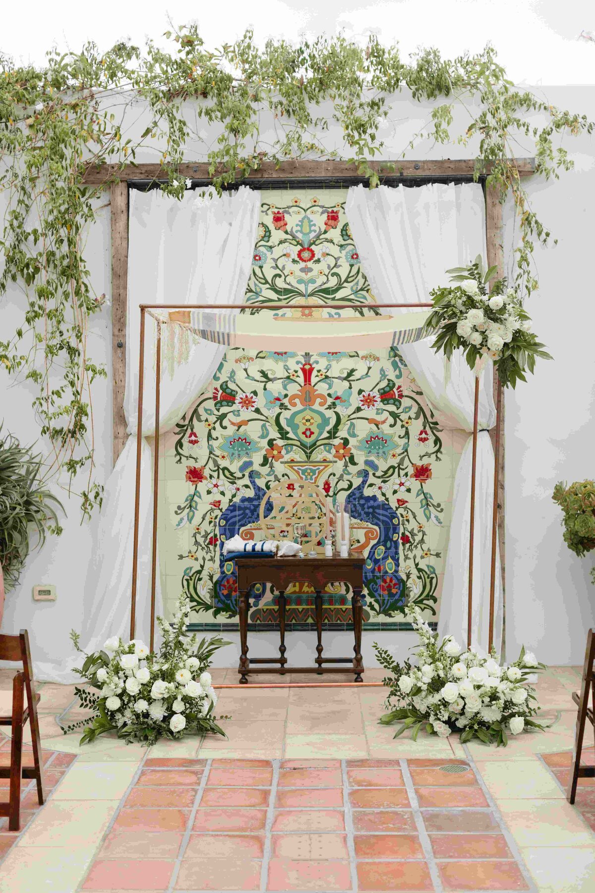Wedding ceremony Chuppah with white flowers and greenery at La Ventura Event Center