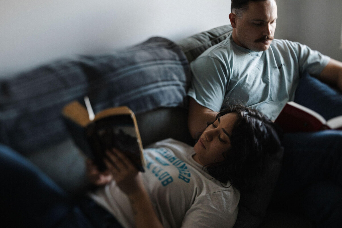 Couple, Cactus & Pine Photography owner and husband reading together on couch for in-home portrait session. Captured by Rachel Richards Photo and Film