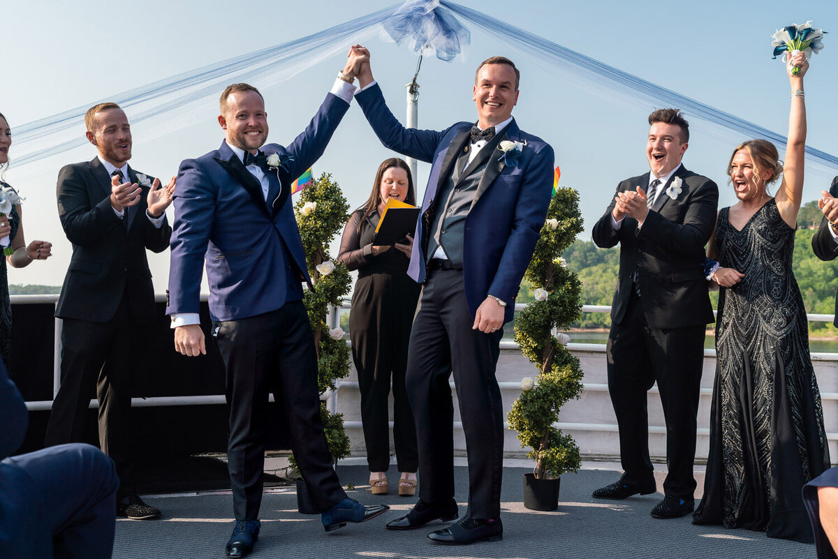 Grooms smile and cheer after wedding in Stillwater, Minnesota.