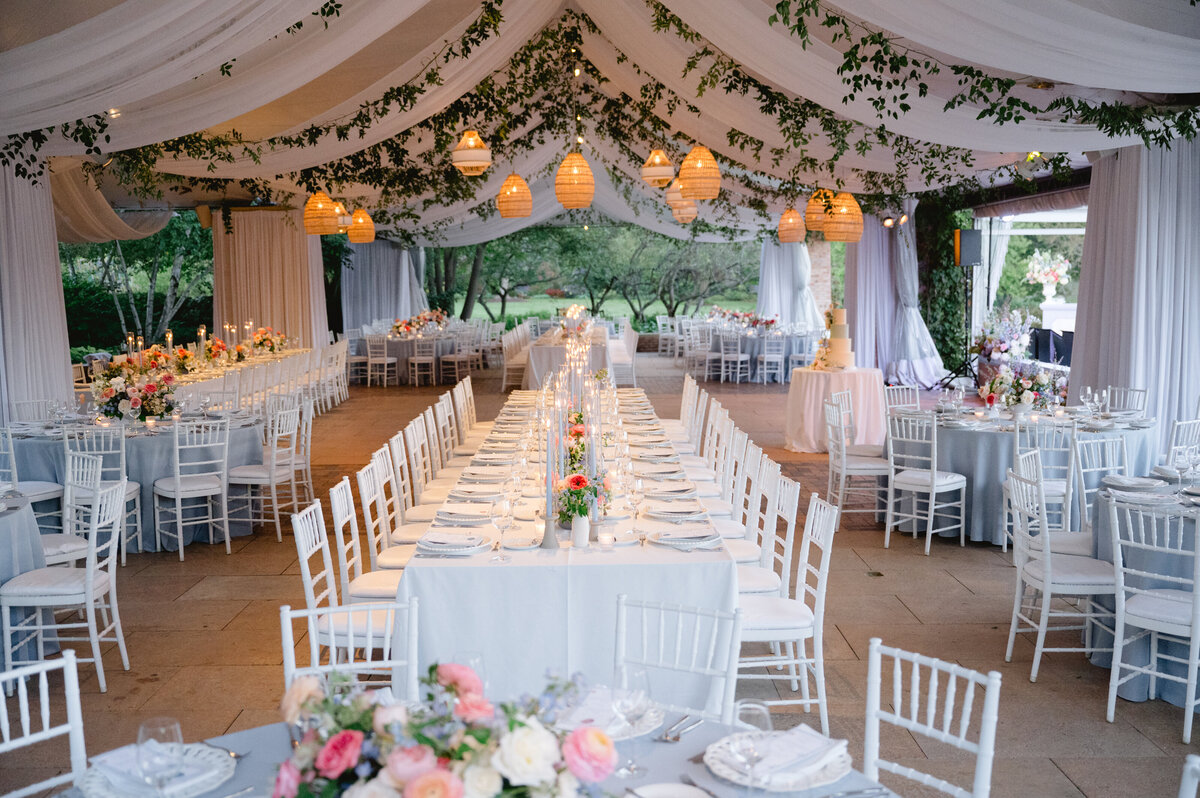 Long reception table under a tent adorned with string lights at the Chicago Botanic Gardens