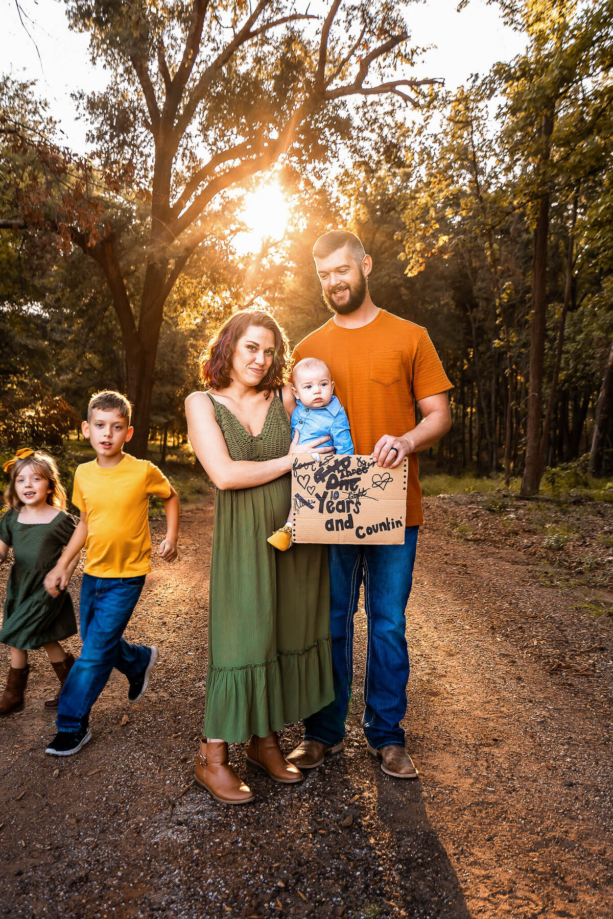 Family of 5 pose for fall photo session at sunset on a dirt road wearing bold colors