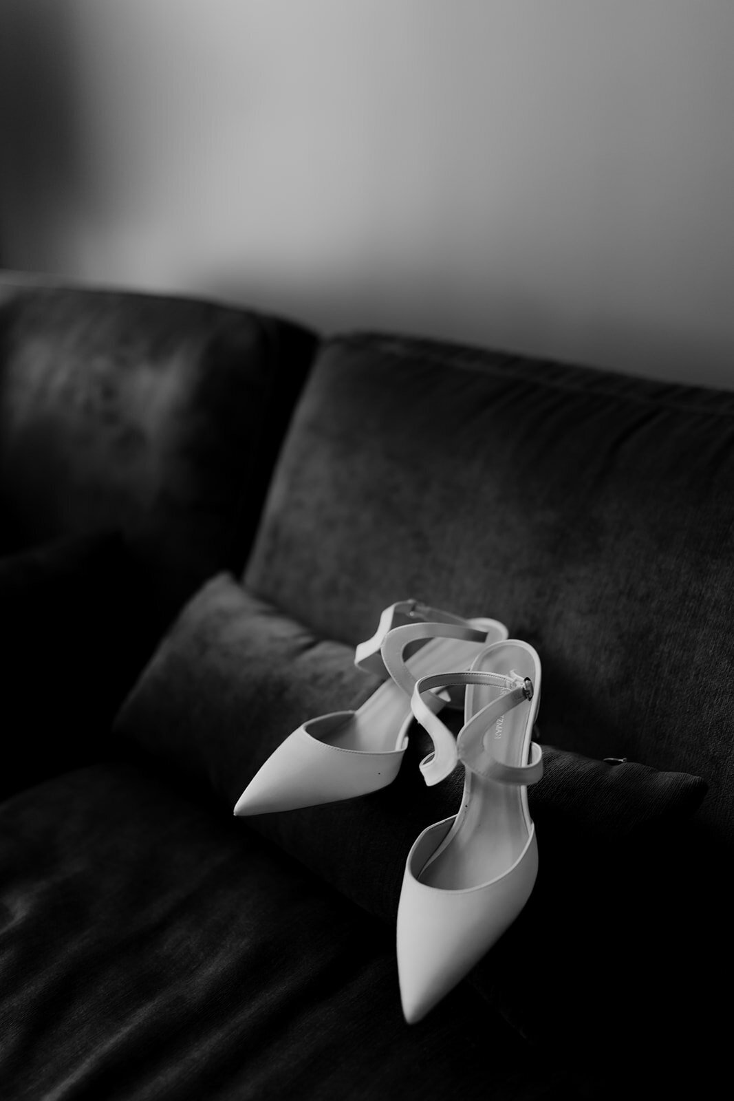Black and white wedding photo of bridal shoes on dark velvet couch at getting ready in Charleston bridal suite