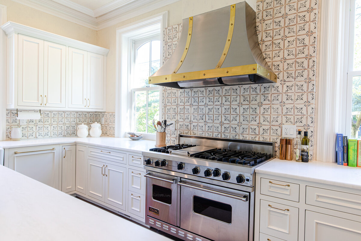 The kitchen features cream white cabinetry, ceramic tile flooring, a hand-painted terracotta backsplash, and a Marble Rhino countertop.