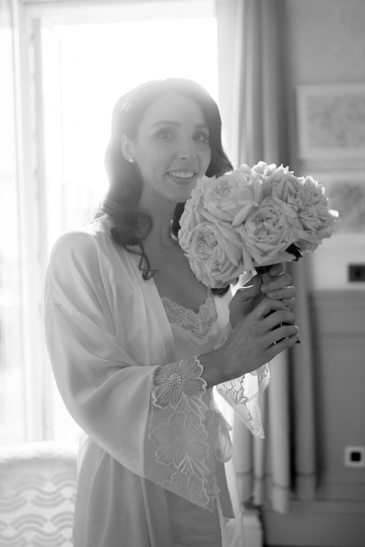 getting ready shot of a bride in a robe smelling her bouquet of flowers in her bridal suite at the ned hotel london for her city chic wedding