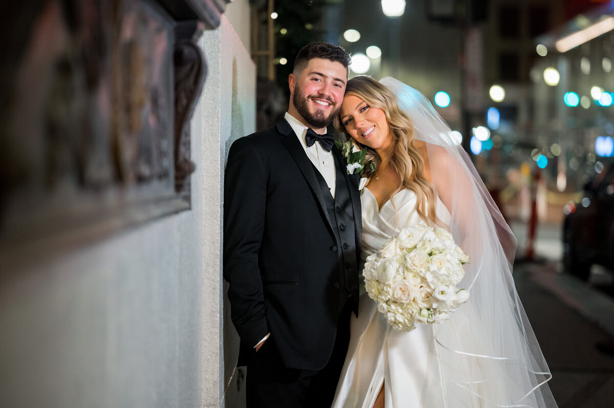 bride and groom smiling for photos on the sidewalk of the omni william penn hotel