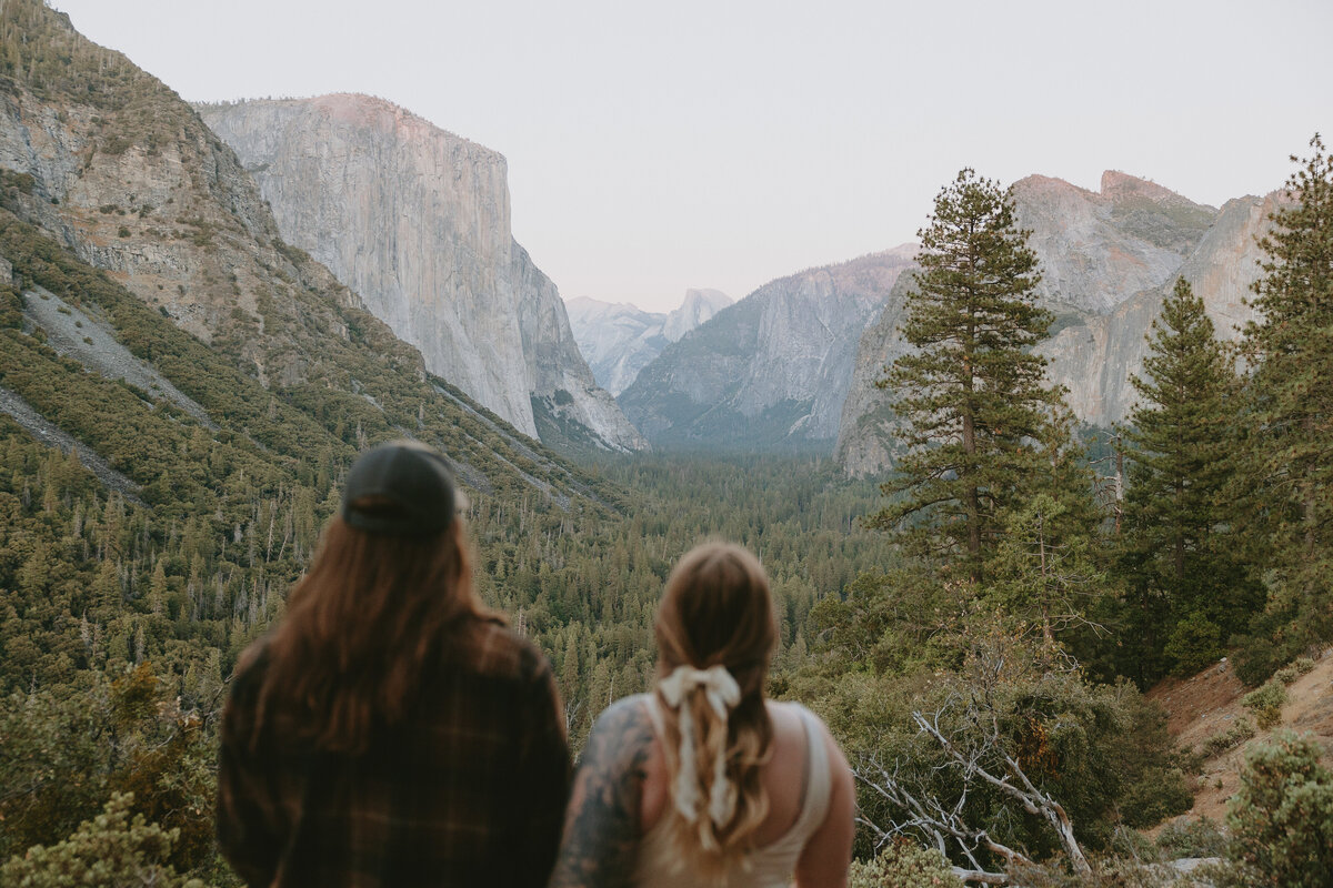 Couple standing looking out a tunnel view during their Yosemite engagement session at sunset