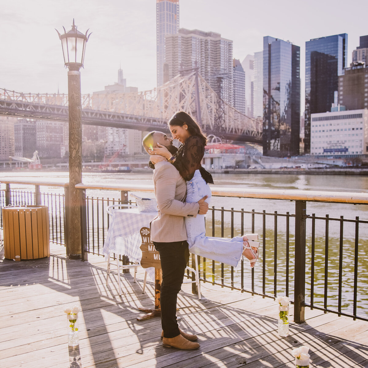 Engaged man picking up the bride after proposing at the pier at roosevelt island during their proposal