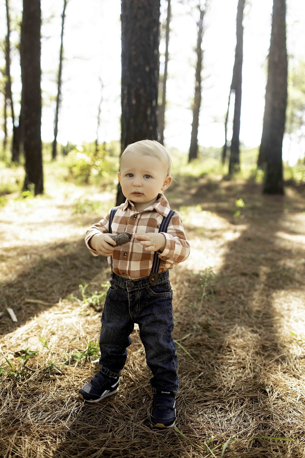 Birthday boy with suspenders and overalls, standing playfully between pine trees, ready to celebrate his special day