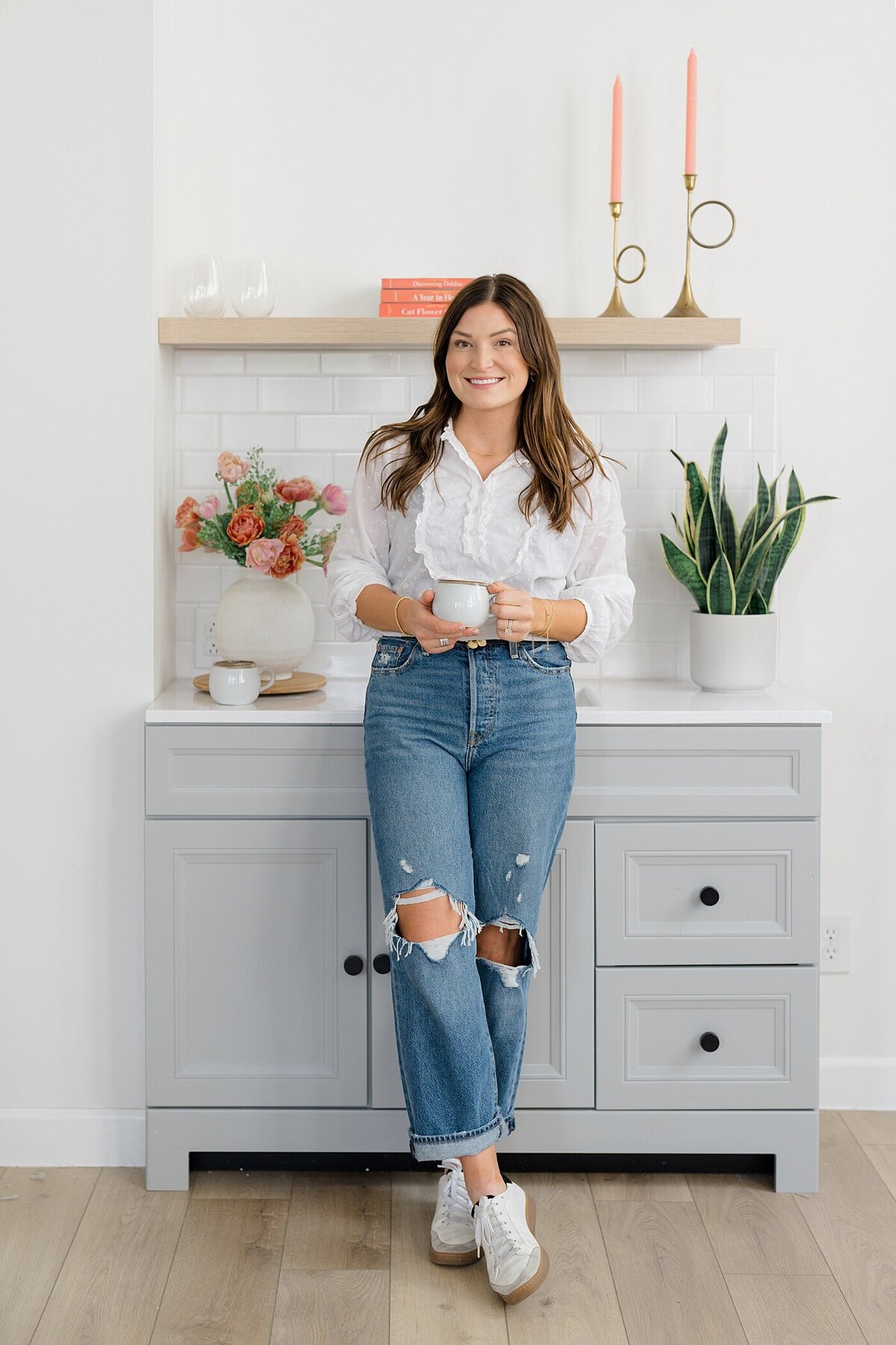 headshot of a small business owner in jeans and a white shirt holding a mug and leaning gainst a counter photographed by branding photographer columbus