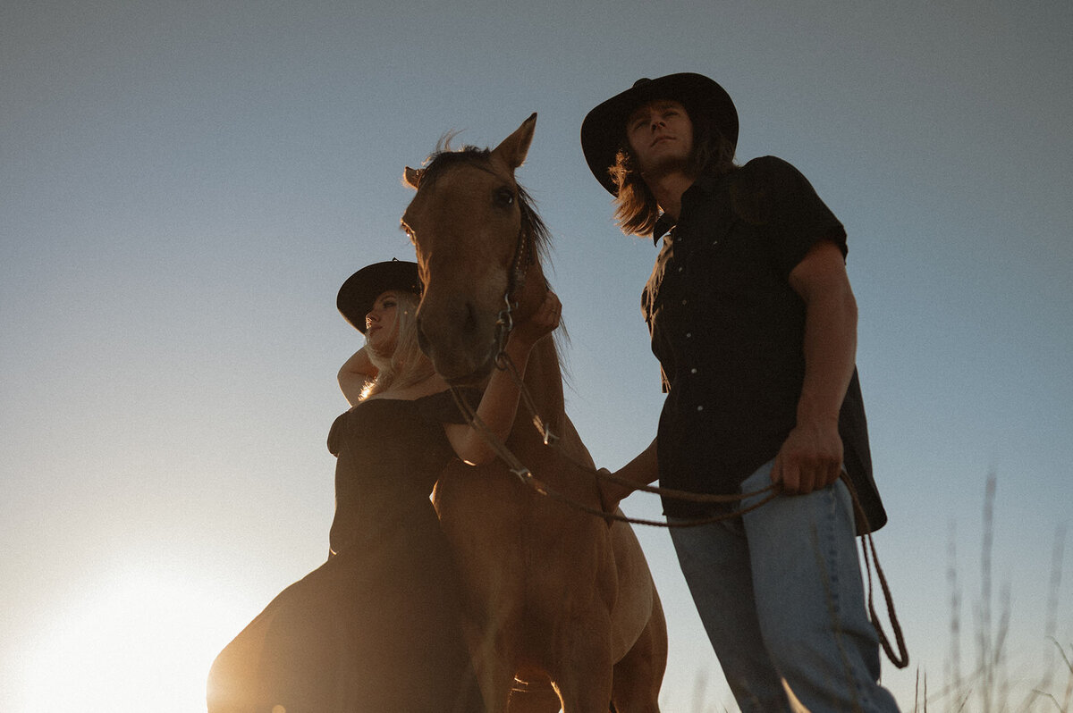 intimate couple portrait with horse during golden hour in a peaceful outdoor setting
