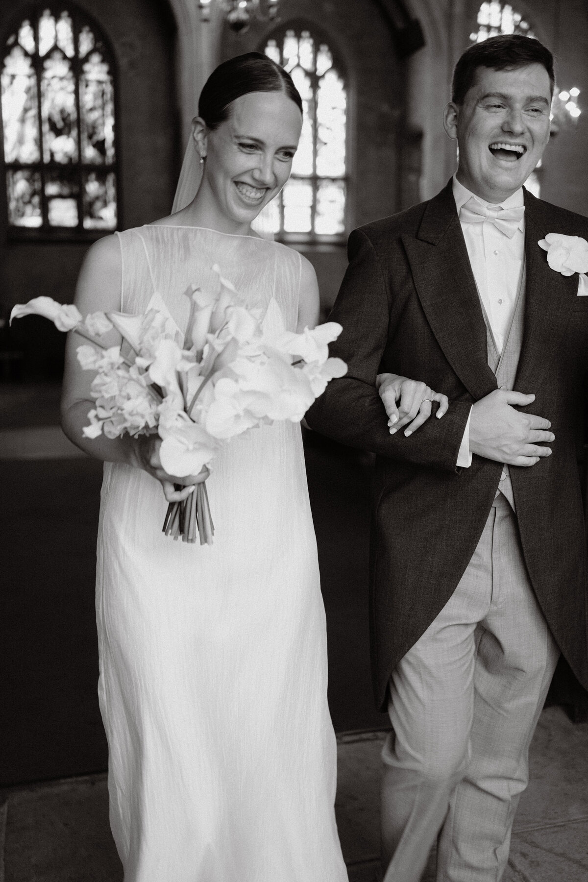 the happy couple leaving the church in B&W grinning after getting married