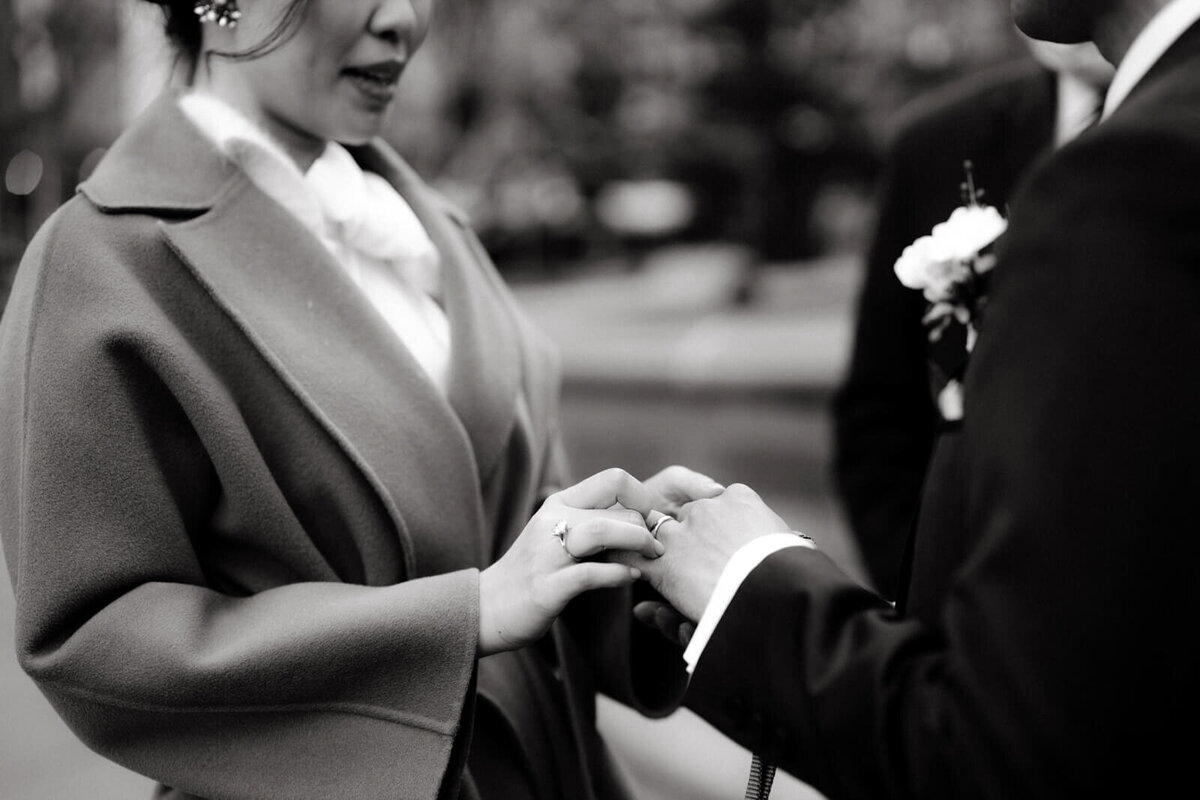 Close-up shot of the bride and the groom's hands, clasped together, while they say their vows.
