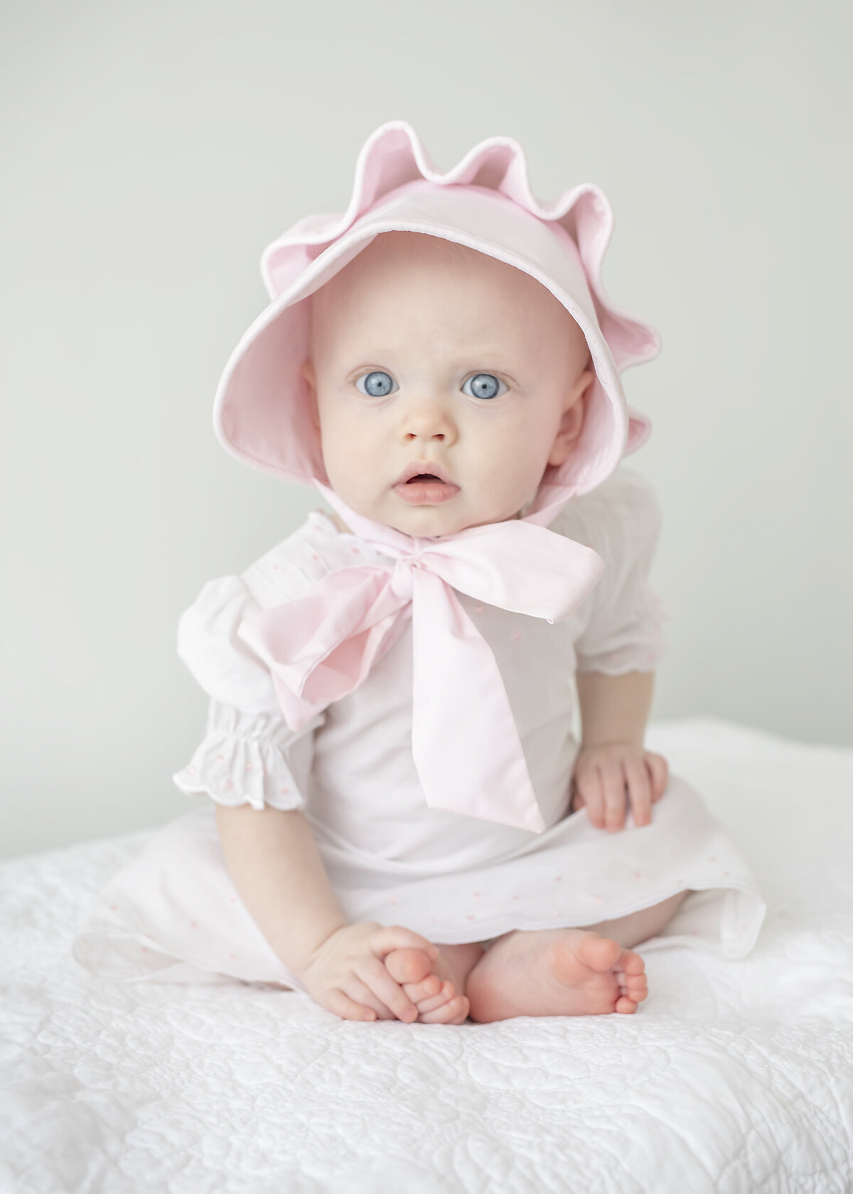 7 month old baby girl photographed wearing a beaufort bonnet hat for her milestone session in studio