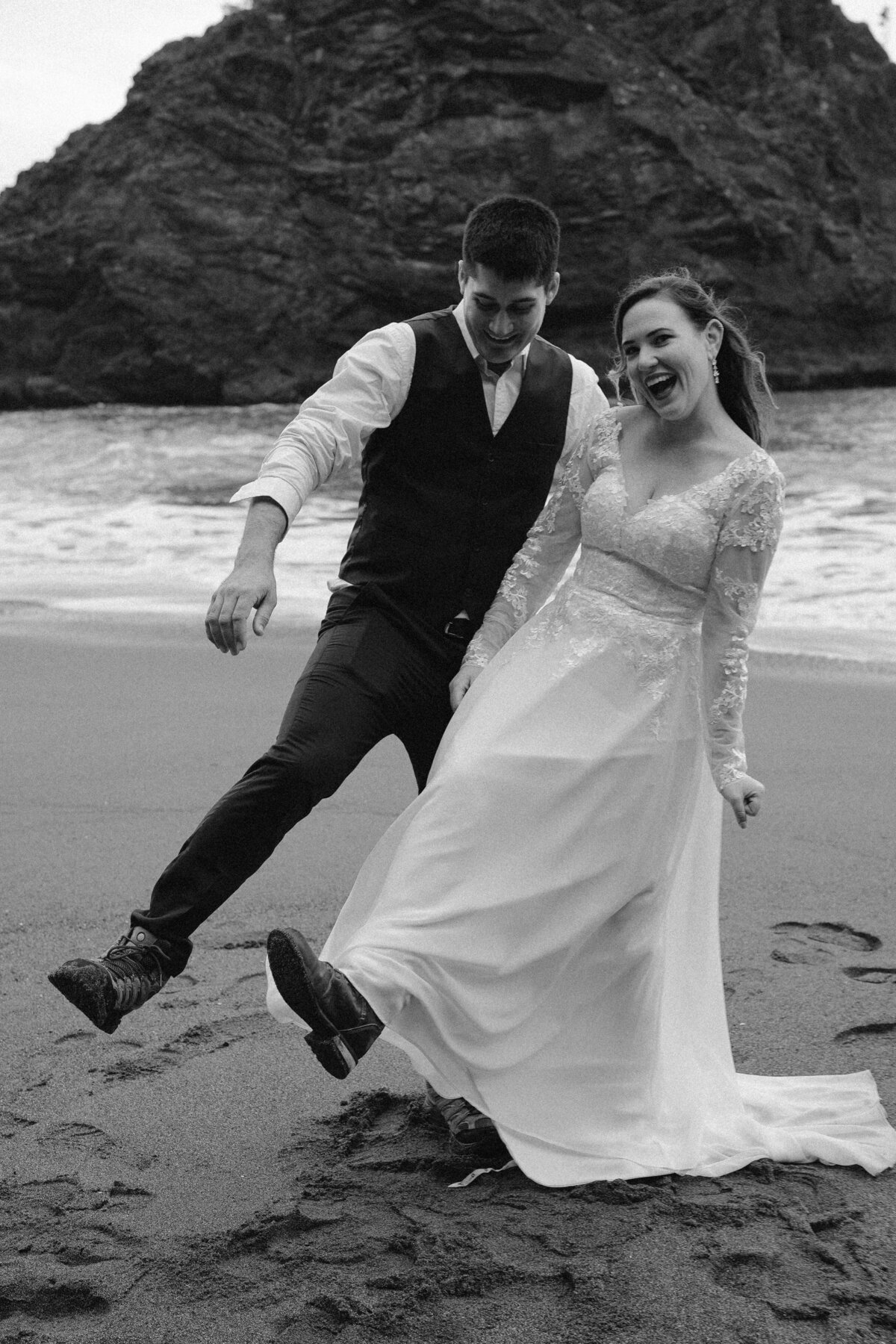 black and white image bride and groom on beach