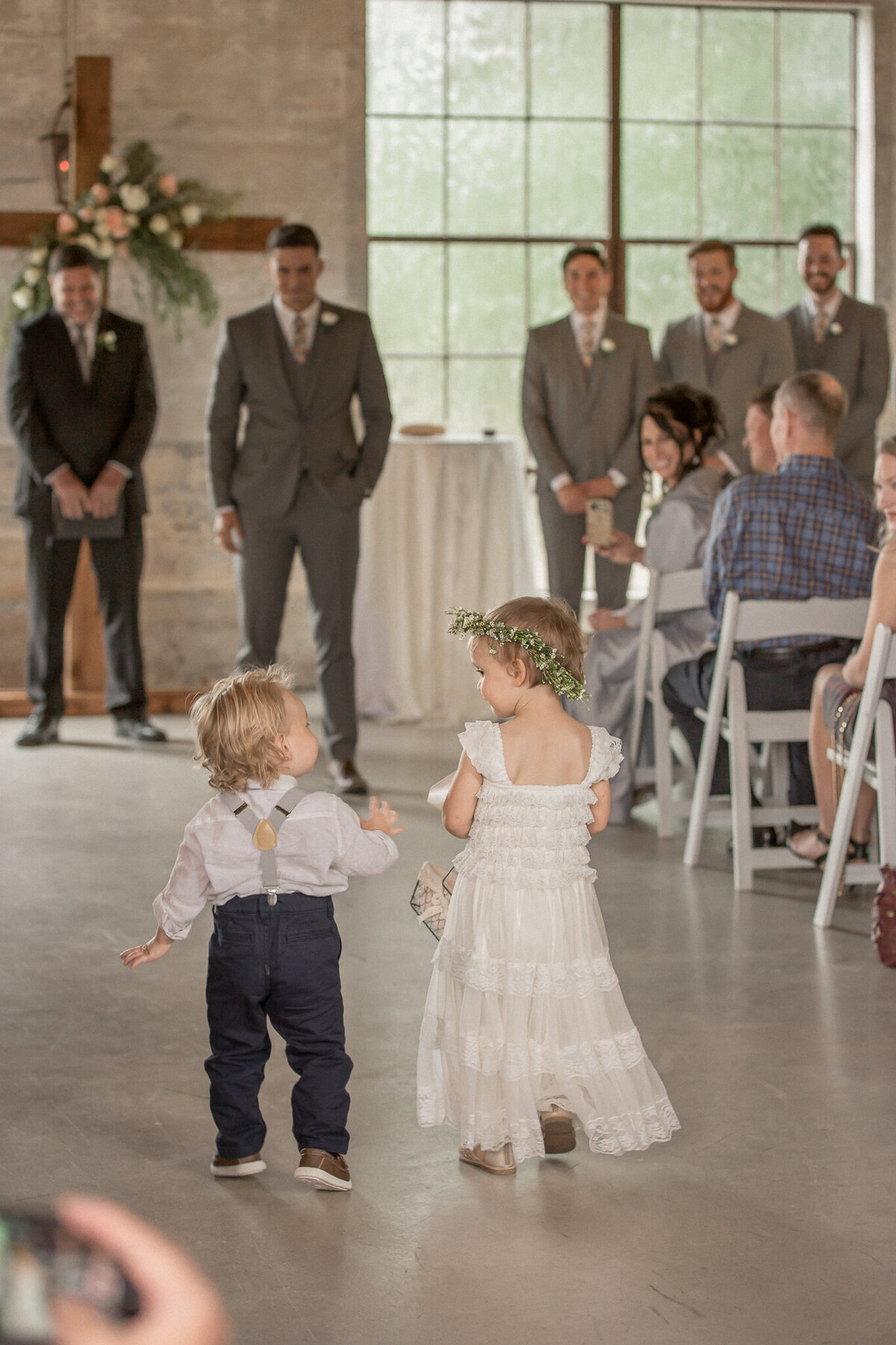 The ring bearer and flower girl enchant the groomsmen and officiant as they proceed down the aisle