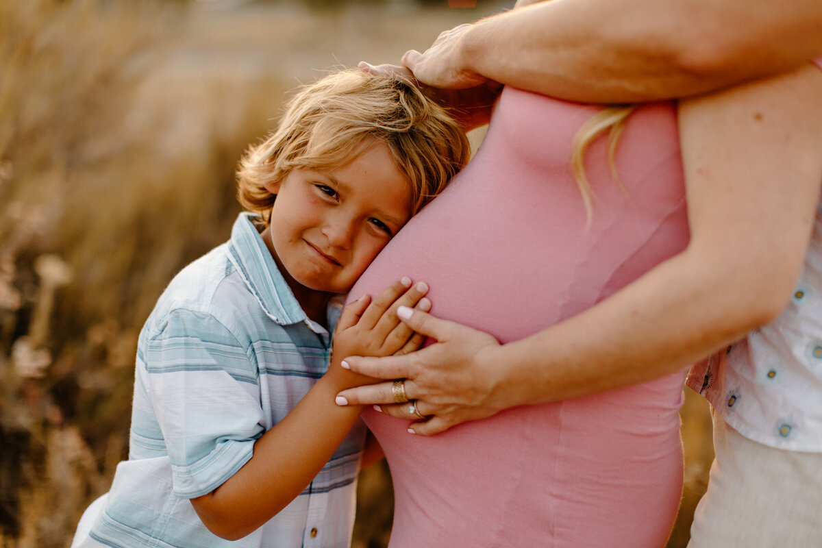 maternity photography with little boy laying head on pregnant belly