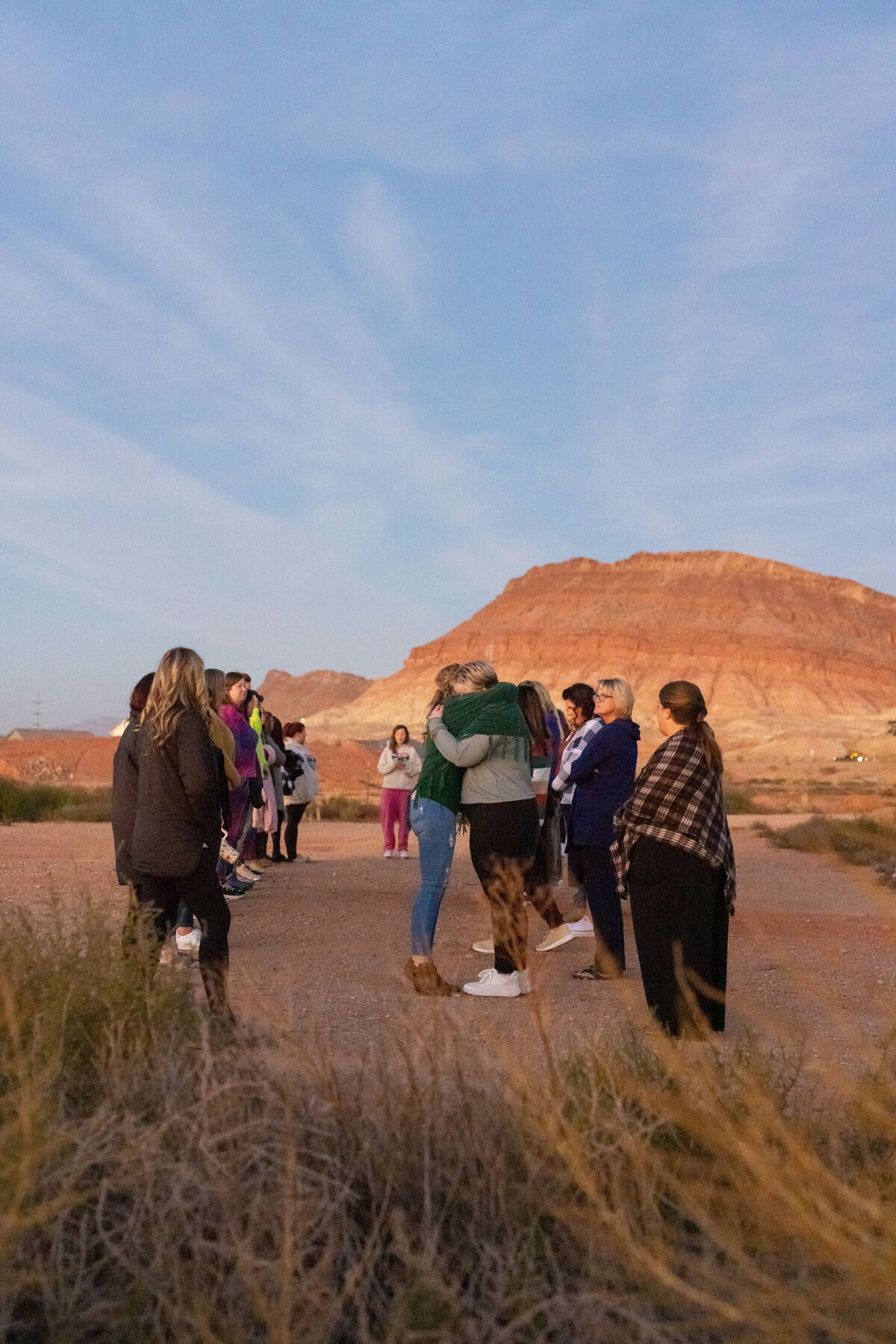 two women hugging each other while big group looks on
