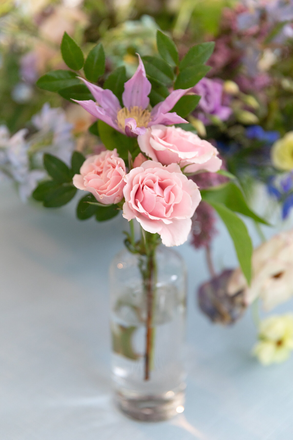 Growing, fresh floral centerpieces with blush garden roses, lilac, blue sweet peas, ranunculus, lavender delphinium, globe allium, clematis, and natural greenery for a tented Bridgerton inspired engagement party at a private home in Nashville, TN.