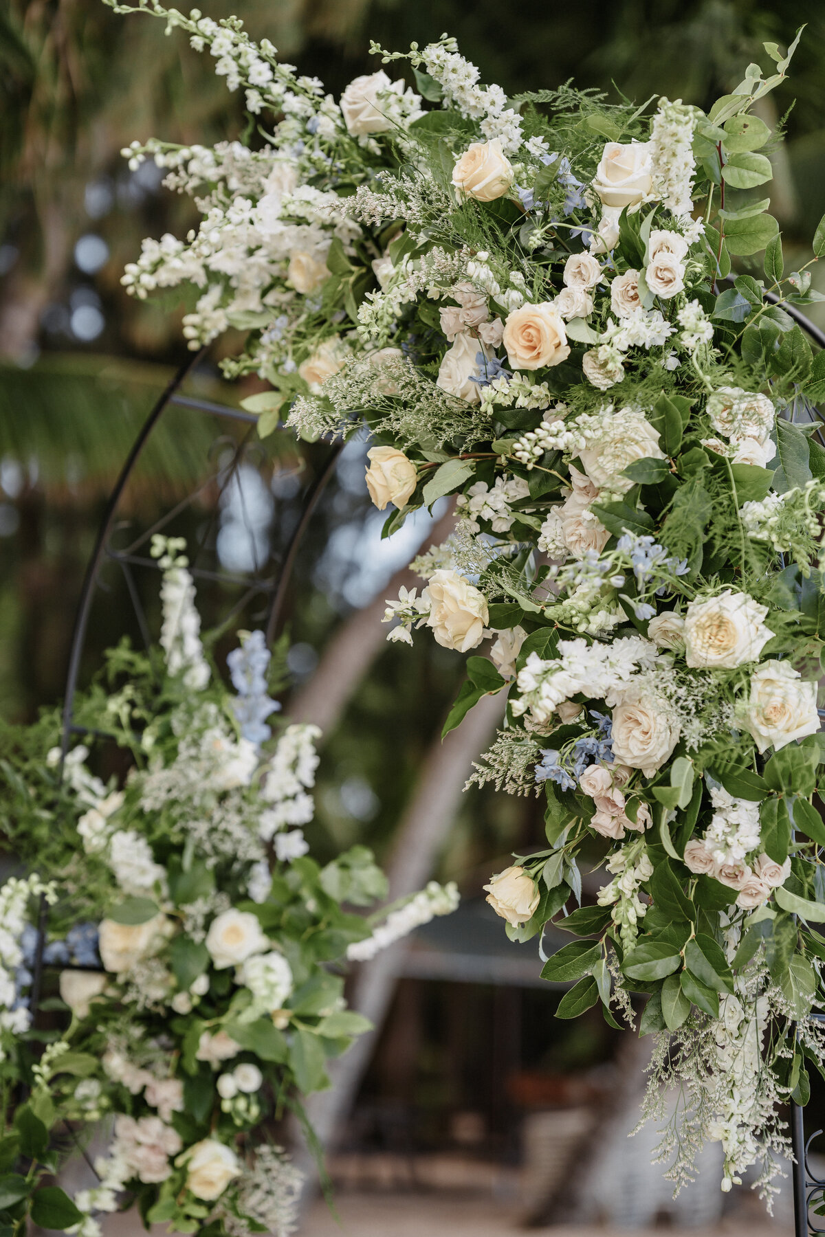 Wedding detail shot of ceremony arch florals that are yellow, ivory, green and blue