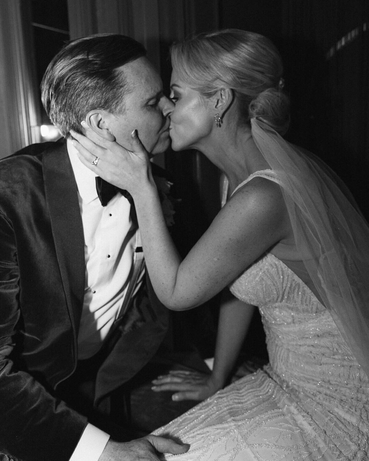 A couple kiss with the bride placing her hand on the grooms face. A very dramatic Hollywood style image.