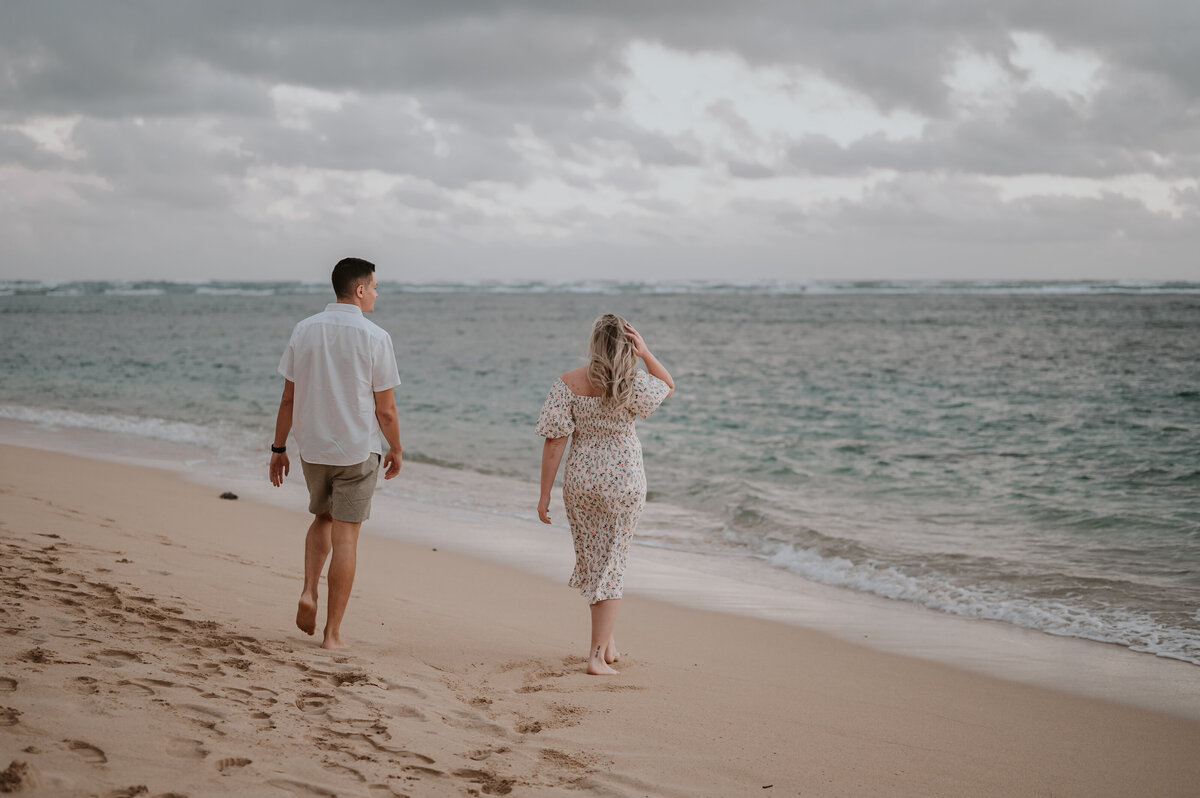 a couple who is recently engaged takes photos with their hawaii photographer at kahala beach at sunrise