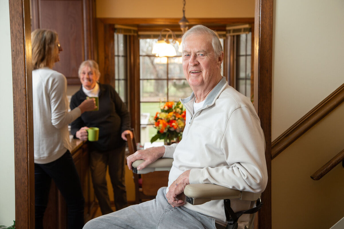 An older man is sitting in a chair in front of a window
