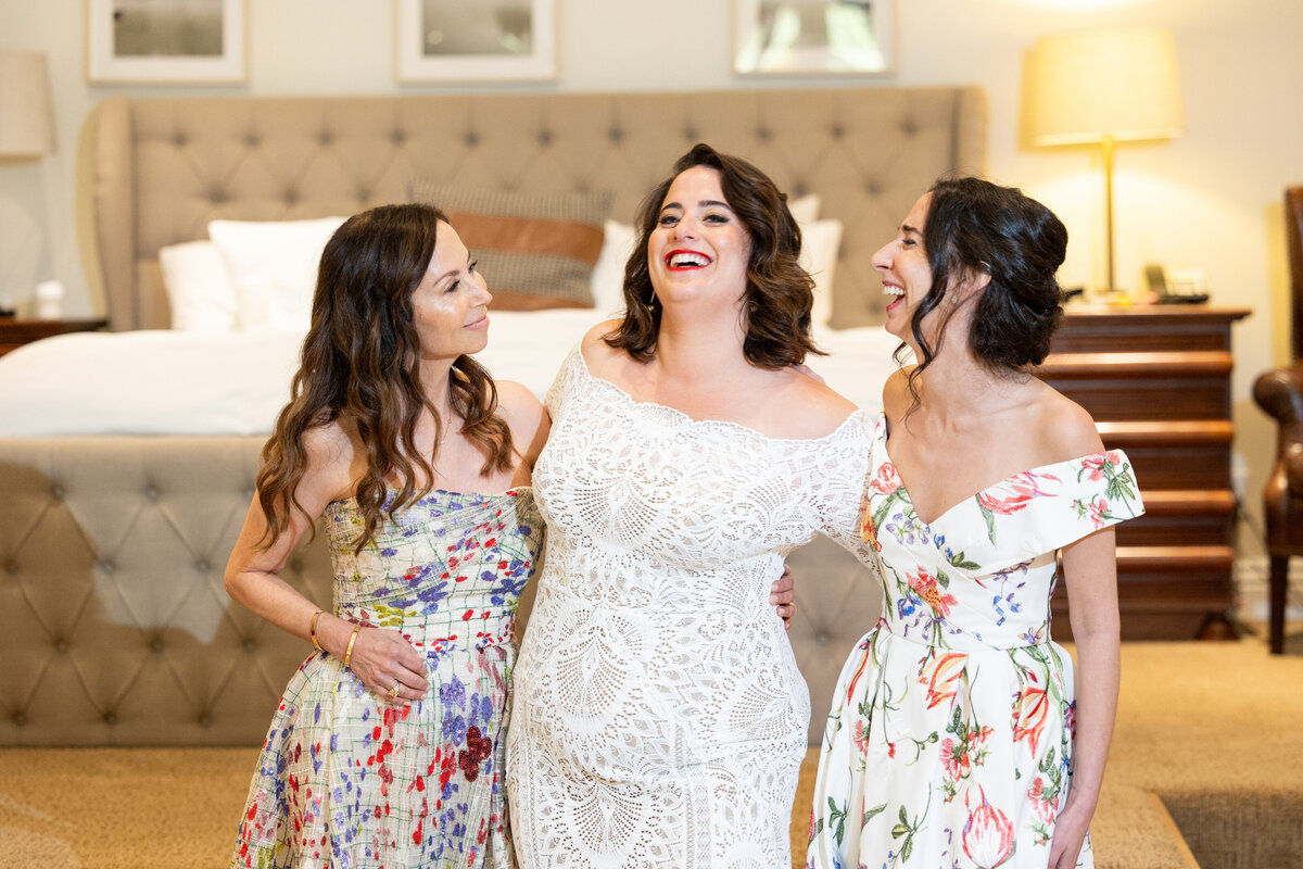 Bridesmaids on either side of a bride as they all laugh