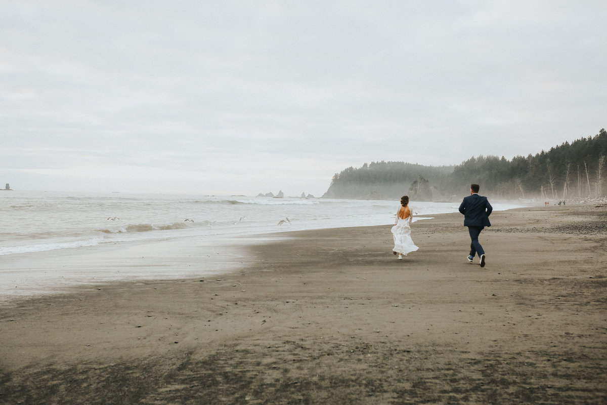 Bride and groom chase seagulls during their elopement wedding at Cannon  Beach on the Oregon Coast.