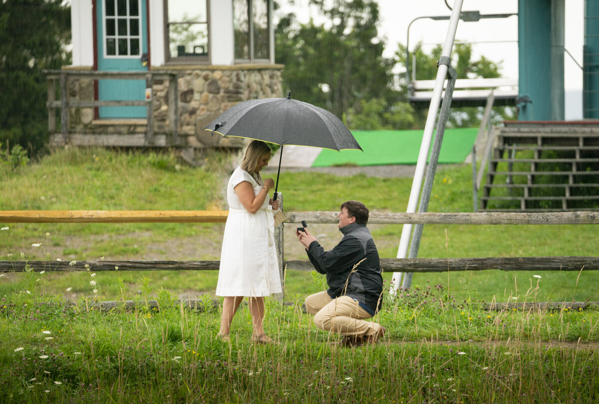 Photo of a man proposing to his girlfriend in the rain
