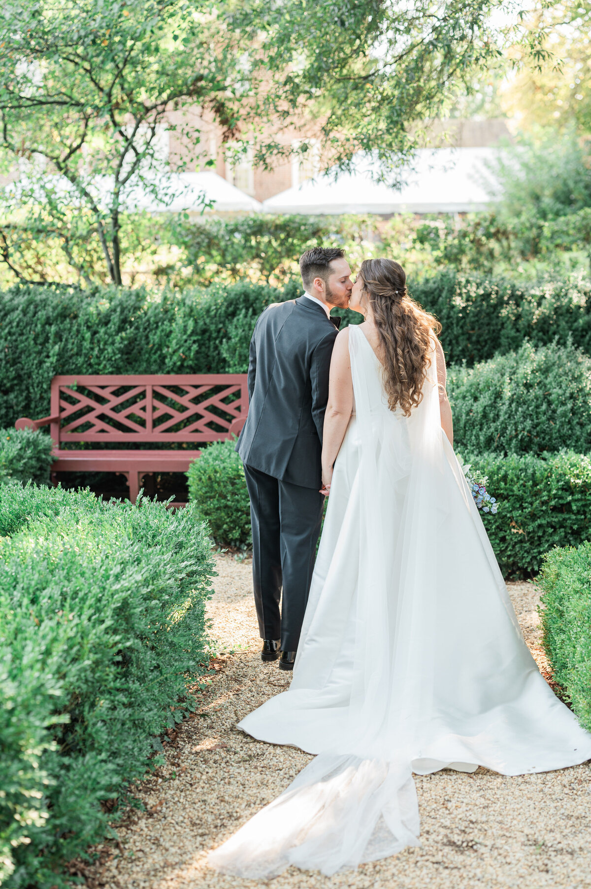 A wedding couple kissing as they walk through a small garden area