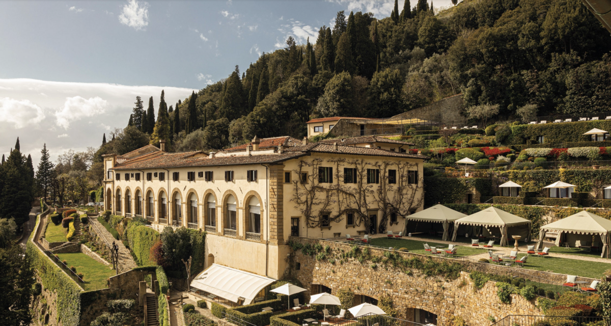 Bird's eye view of Borgo Santo Pietro, a refined Italian country borgo with classic stone buildings spread out between cypress ree lanes, gardens and forests