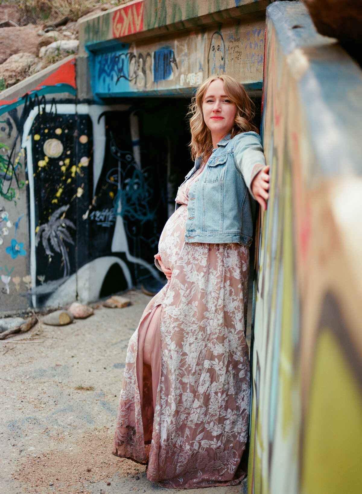 woman holds pregnant belly by graffit