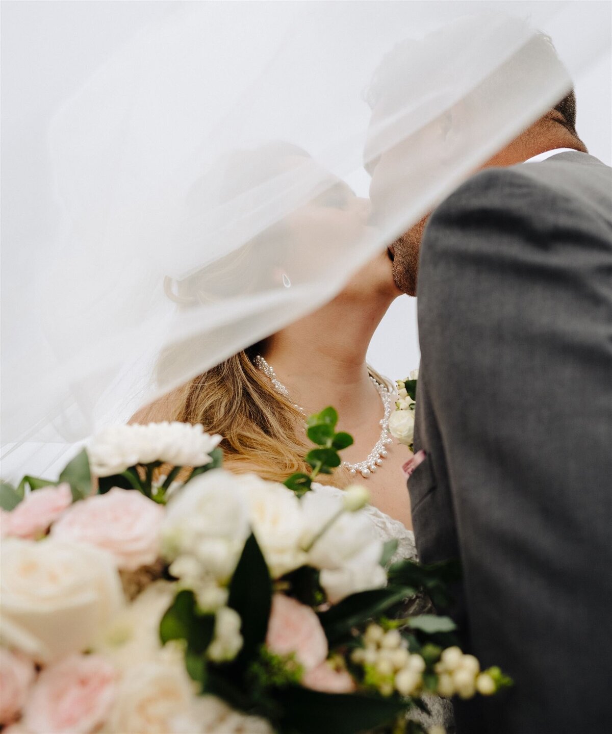 a married couple kissing under a veil