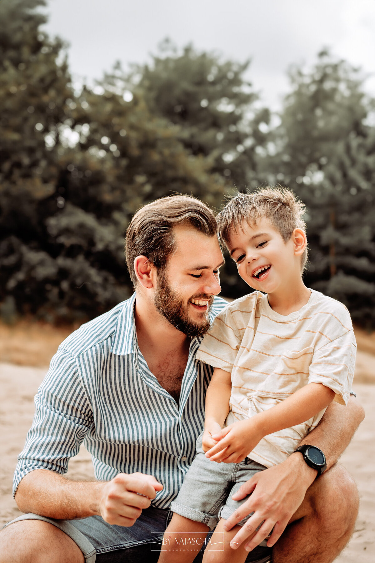 Zoon zit bij zijn vader op schoot in de duinen en lachen lief en gezellig met elkaar in de Bedafse Bergen Uden