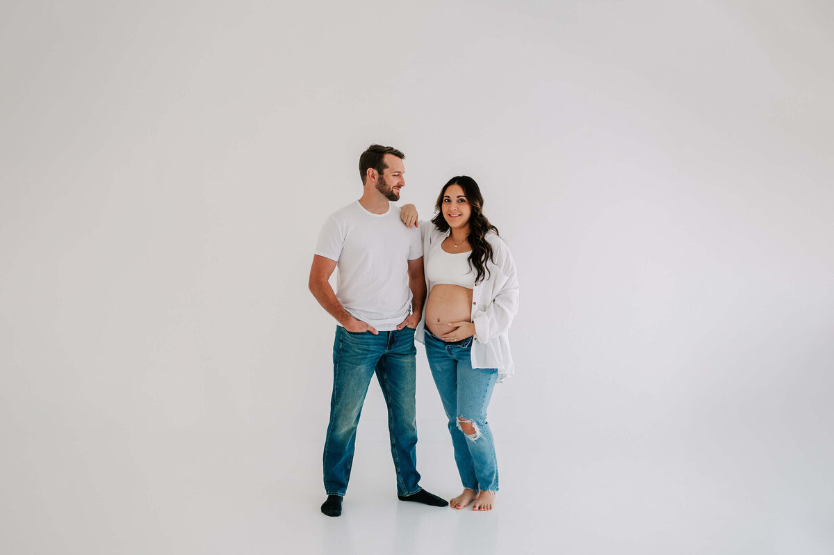 pregnant couple in white tees in maternity photography studio in Joplin MO