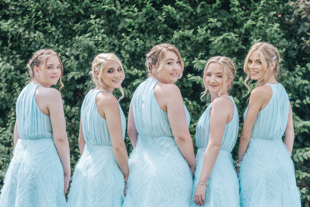Bridesmaids in blue dresses looking over their shoulder