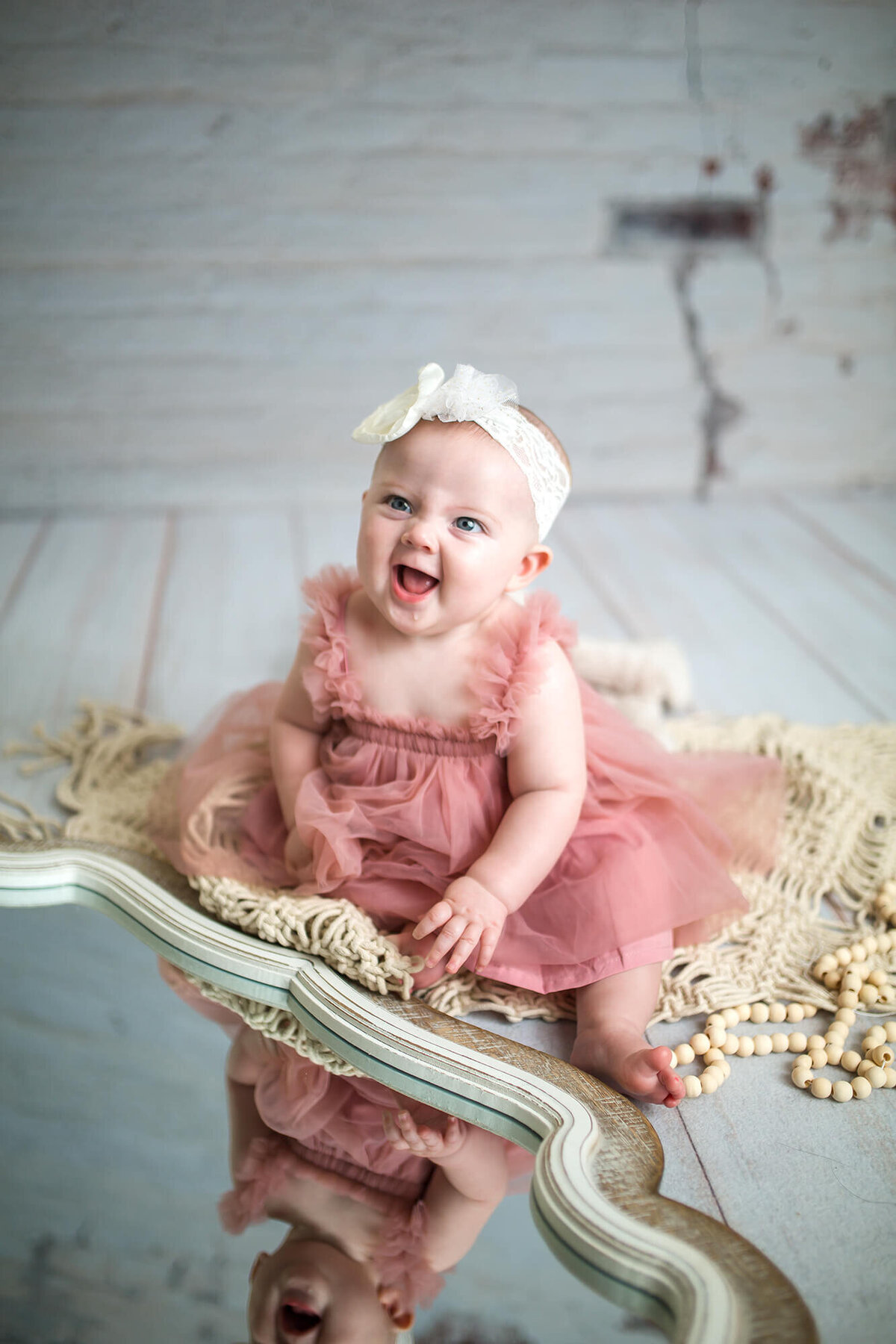 Laughing little girl in pink tutu dress looking in a mirror at herself 