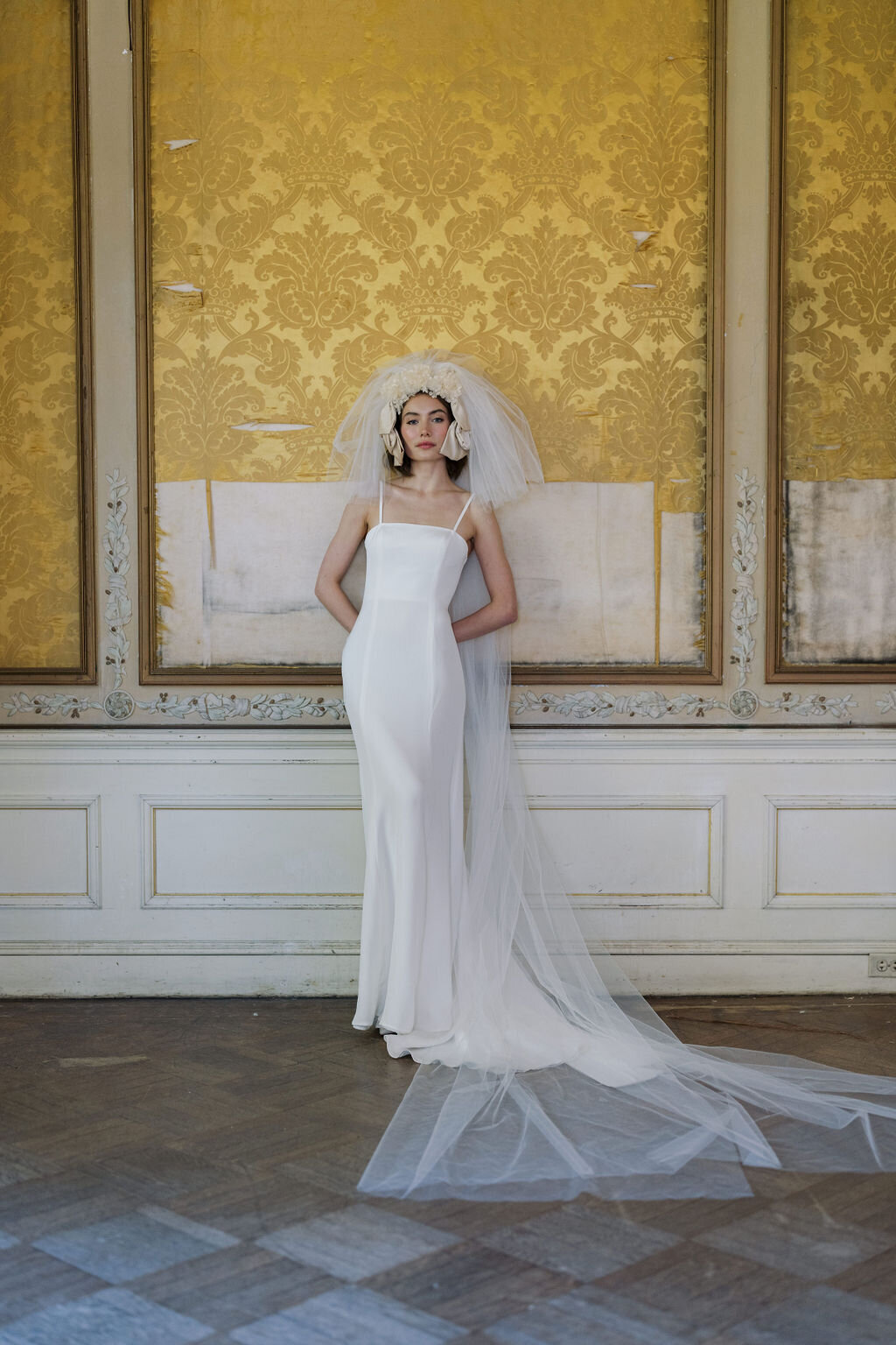 bride wearing wedding dress leaning against wall in yellow room mansion