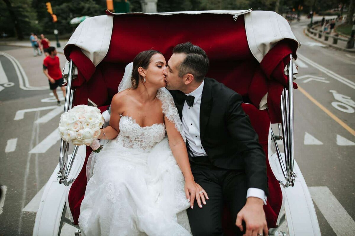 Bride and groom celebrating being happily married on a carriage in New York City.