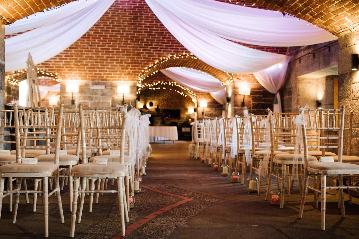 A room filled with lots of white chairs in rows ready for a wedding ceremony