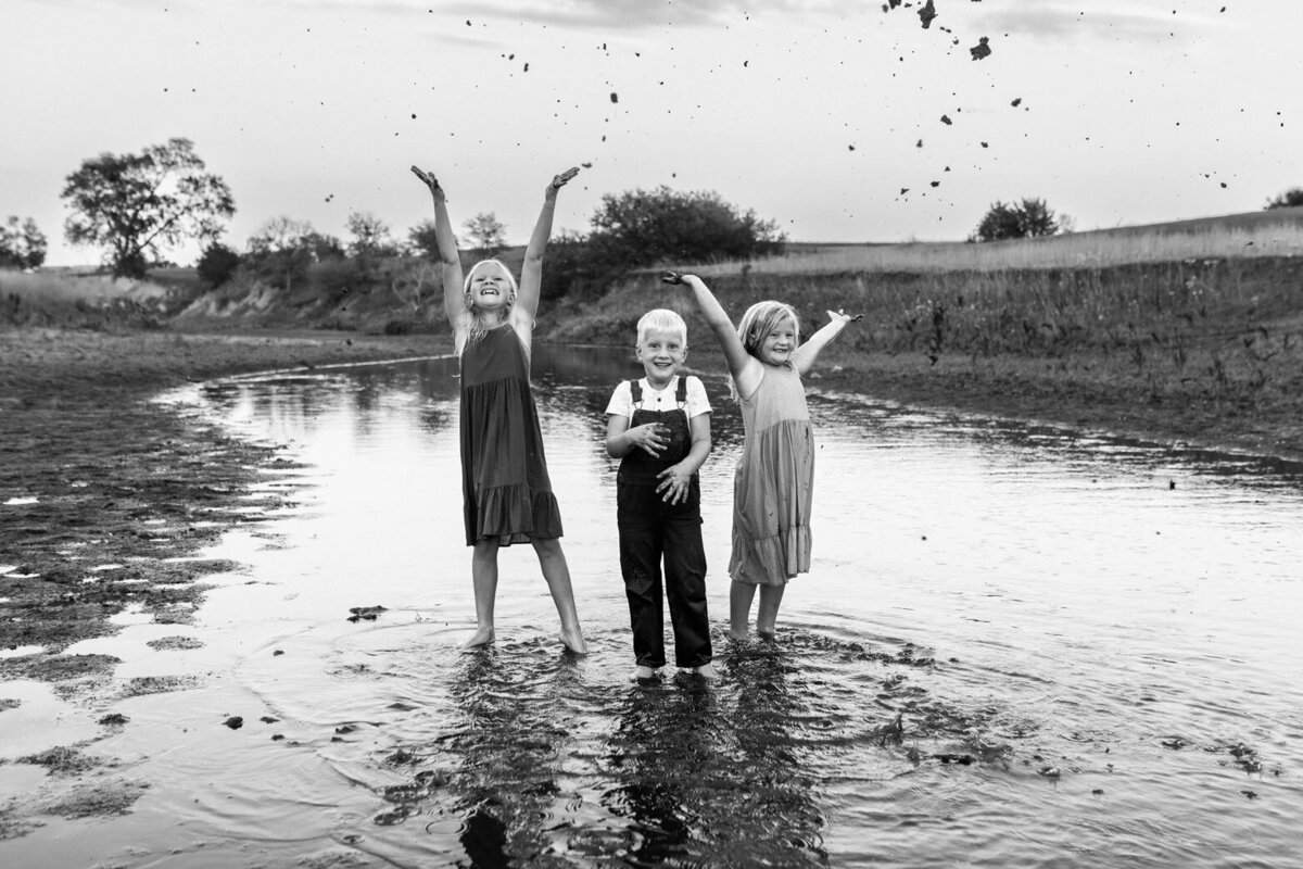 siblings-throwing-mud-in-air-in-creek