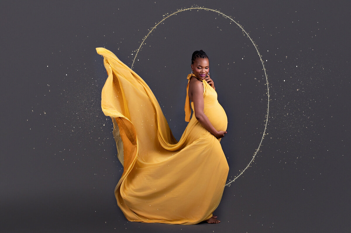 Expecting mom posing confidently in striking yellow dress.
