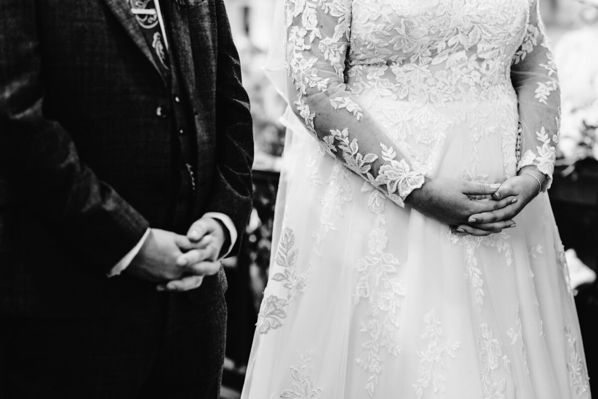 Black and white detail shot of bride and grooms hands folded