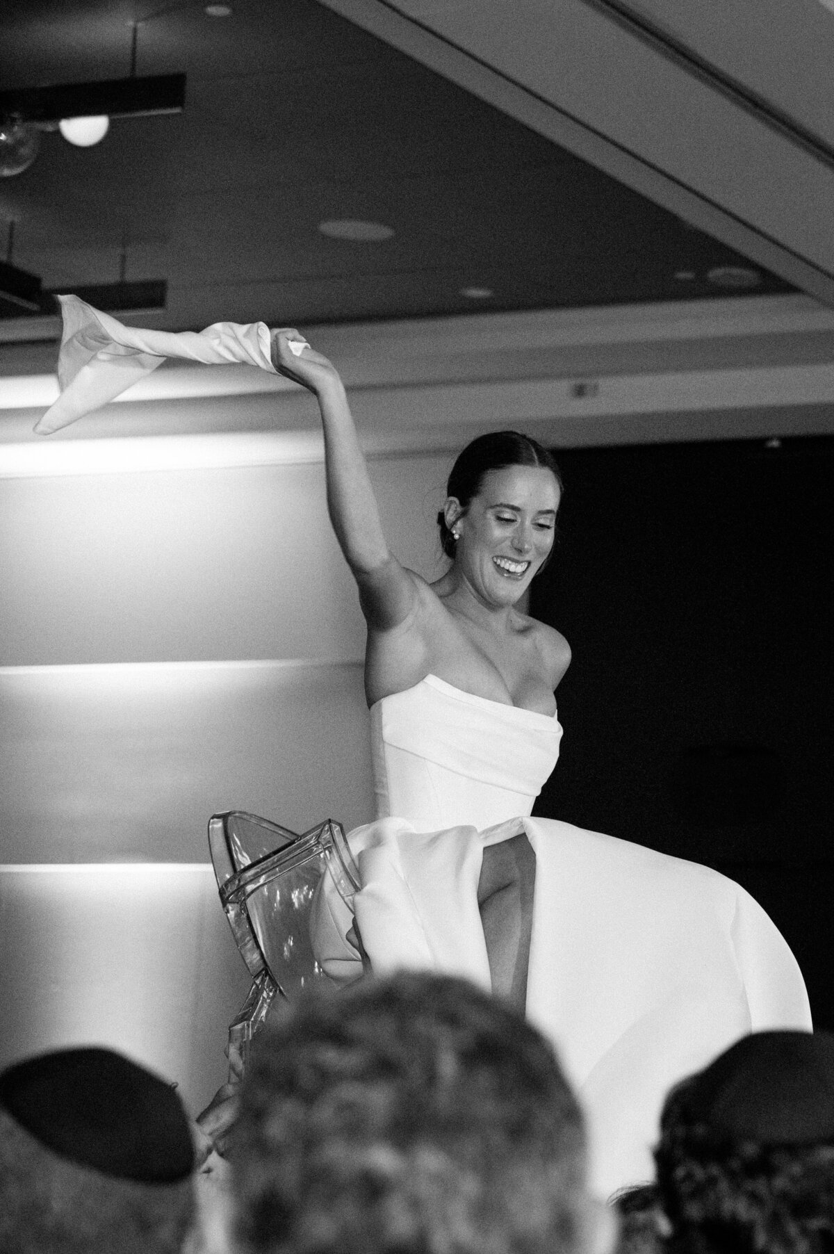 Black and white photo of the bride being lifted on a chair during the hora dance at a Jewish wedding in Toronto.